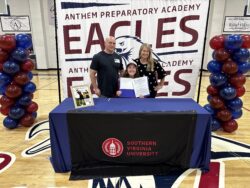 Student with family behind a table with Southern Virginia University logo