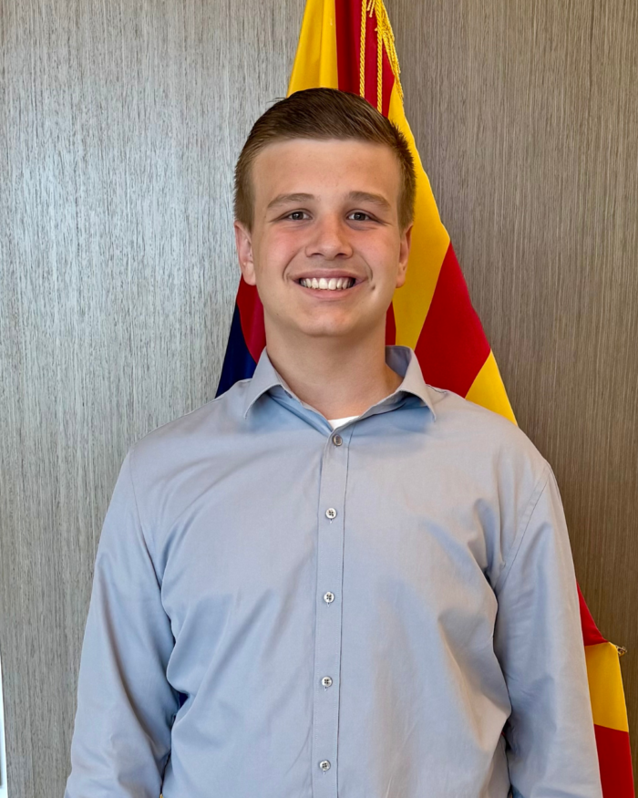 Student posing in front of a flag