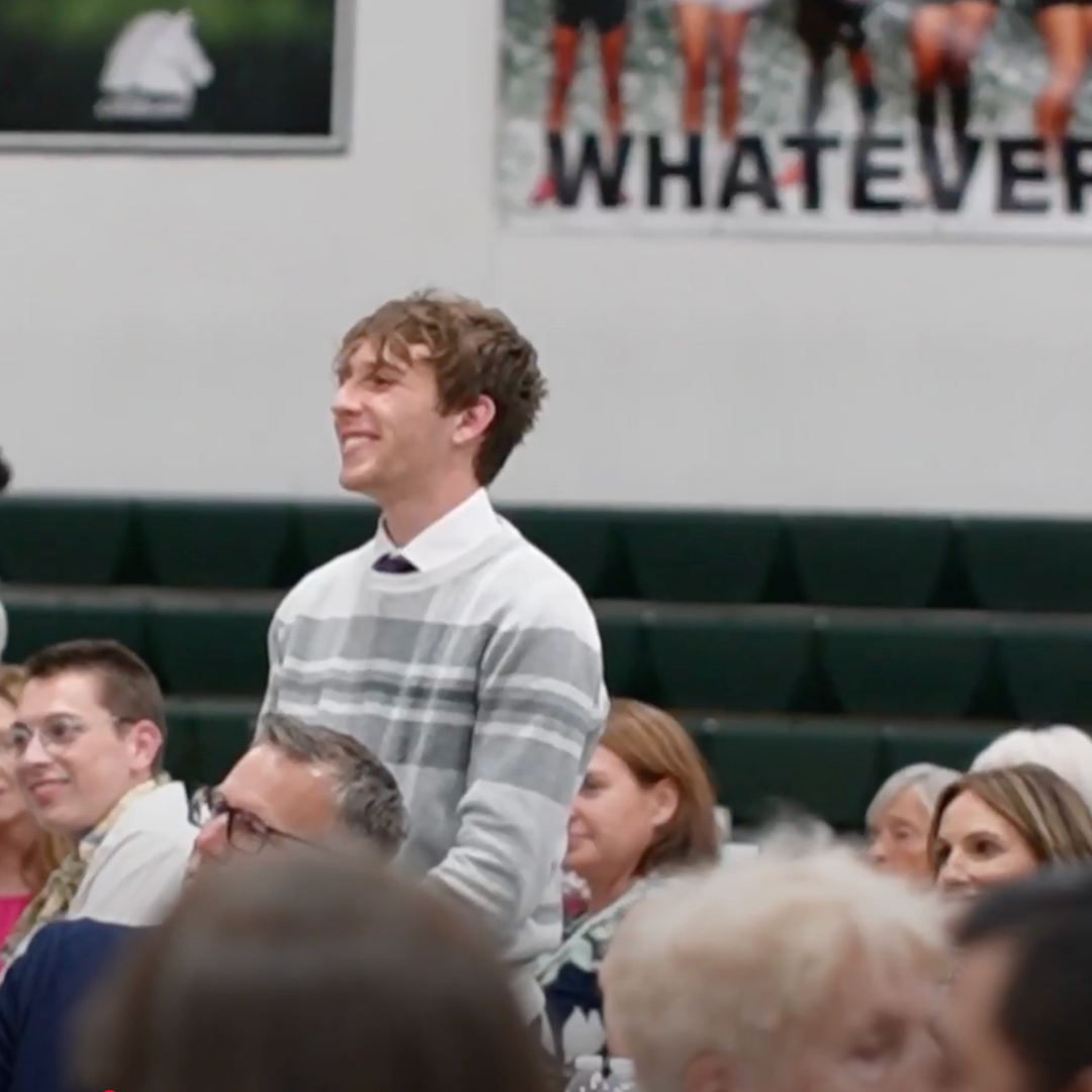 Student standing in a crowd of seated people