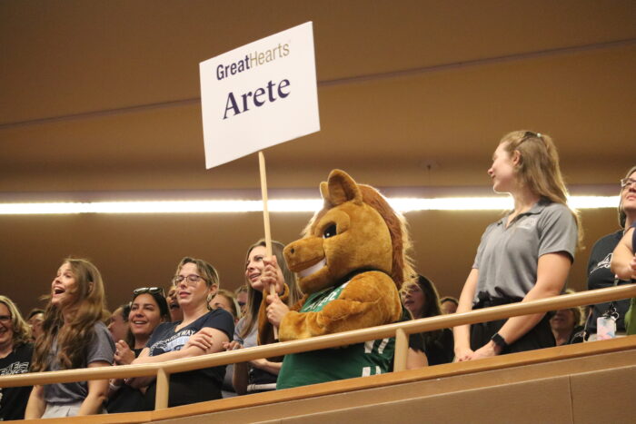 Arete mascot holding a sign