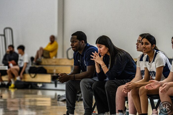 Coach on bench with girls basketball players