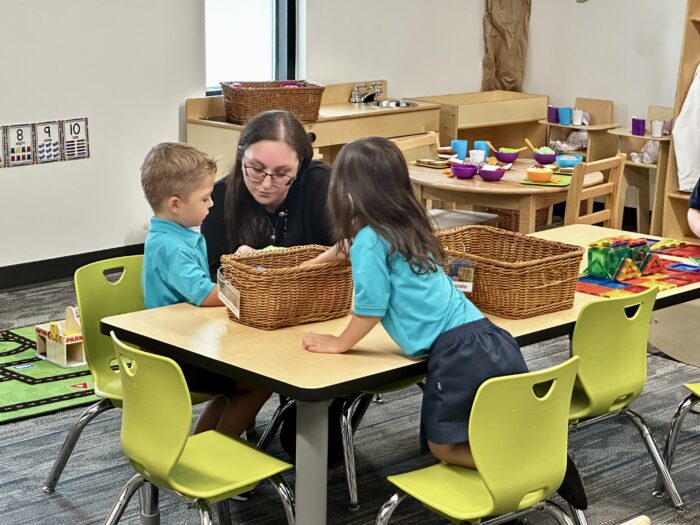 Preschool teacher with two students at table