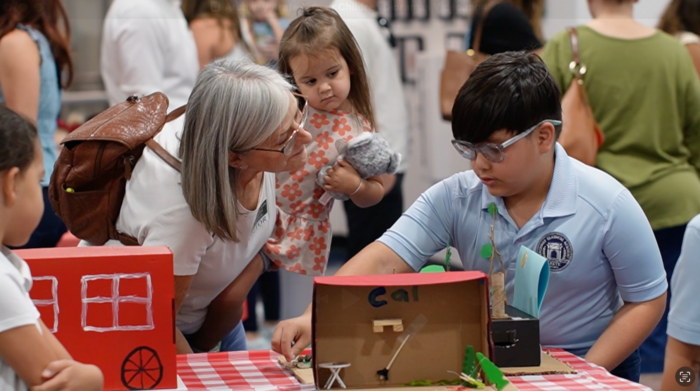 Student showing diorama to a parent