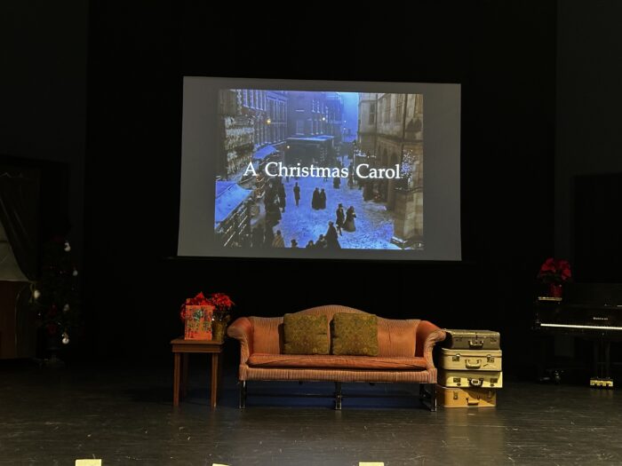 A Christmas Carol movie playing on a stage with furniture