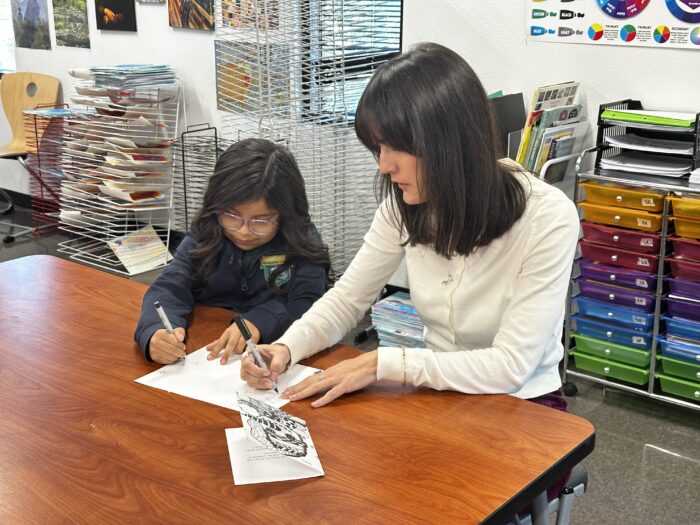 Girl drawing with teacher