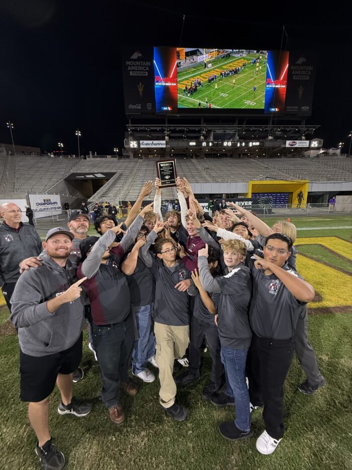 Trivium Prep football players and coaches holding an award on a football field