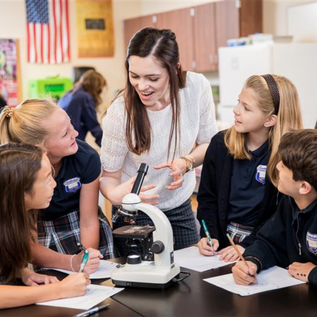 Lab with teacher and students around microscope
