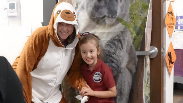 Teacher dressed like sloth posing with a student