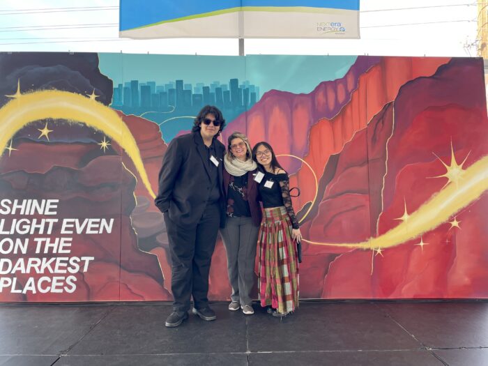 Students with art teacher in front of mural