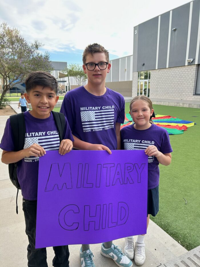 Three Students holding a purple Military Child sign