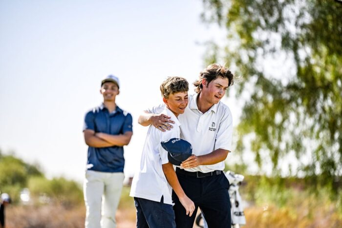 Student golfer hugging his caddy at tournament