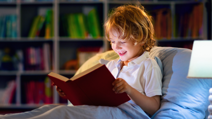 Child reading a book in bed