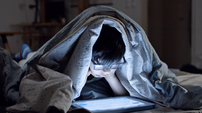 Child watching screen in bed