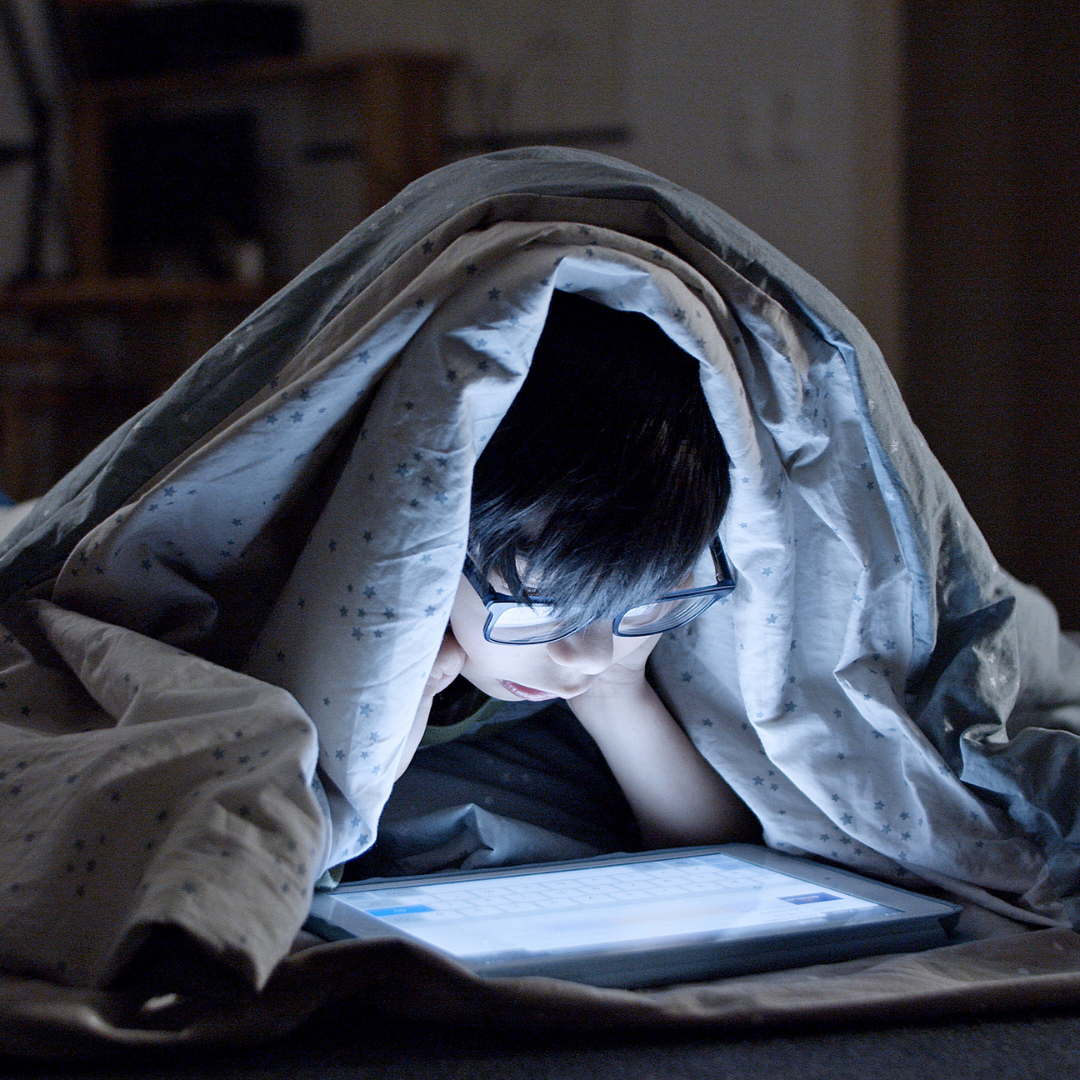 Child watching screen in bed